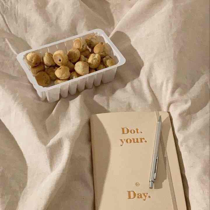 ベージュ調の寝室のベッドにノートとペン、おやつが置かれた落ち着いた空間