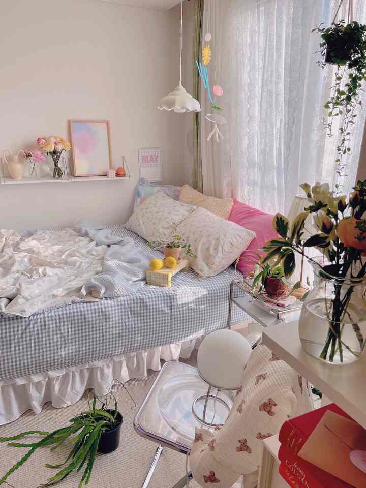 Beige and blue toned bedroom featuring a poster, curtains, and various plants creating a cozy natural atmosphere