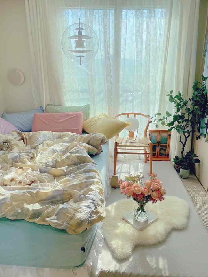 ホワイトとウッドトーンの寝室、カラフルな枕とラグの上の花飾りが温かみのある雰囲気を演出しているインテリア