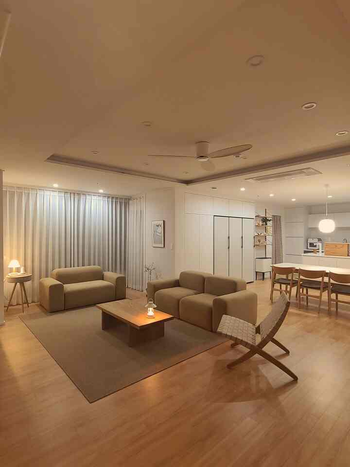 Beige and natural wood tone living and dining room with simple modern furniture layout creating a comfortable atmosphere