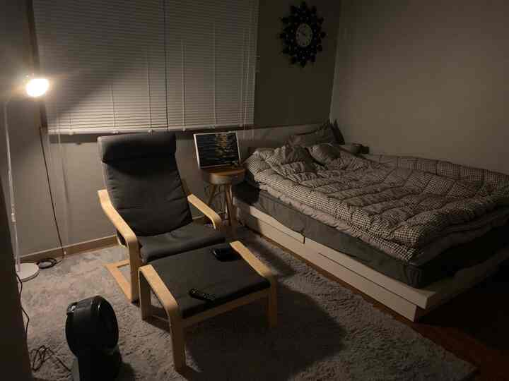 Gray and wood-toned studio bedroom featuring a POÄNG armchair and bed with cozy atmosphere