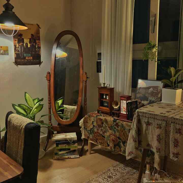温かみのある木目調とヴィンテージの花柄ファブリックが調和したリビング、アンティーク家具と大きな木製全身鏡が印象的な空間