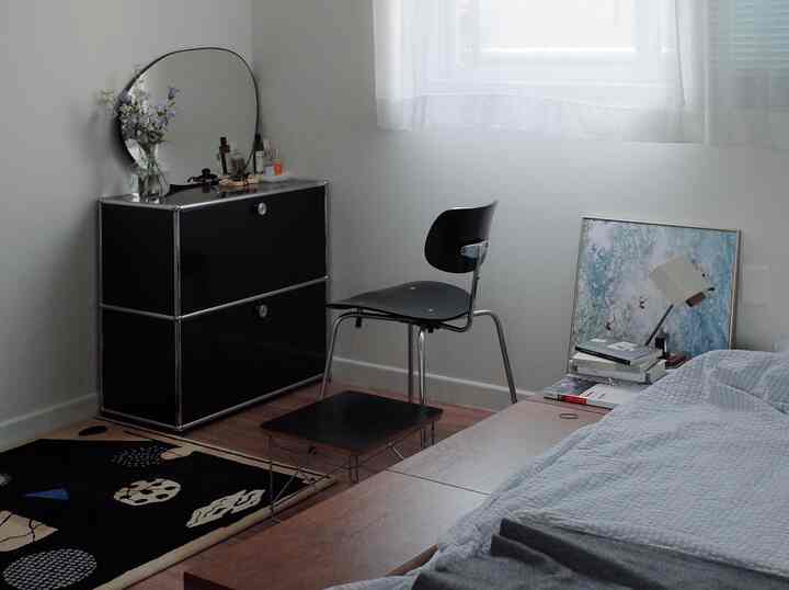 A modern bedroom with a harmonious blend of white and black tones, featuring black furniture and a patterned rug