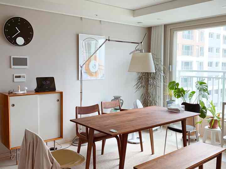 ベージュ調のダイニングルーム、木製テーブルと椅子、植物、フロアランプが配置された雰囲気のあるインテリア