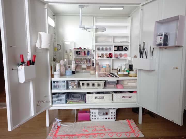 White-toned vanity space featuring acrylic organizers, LED lighting, and storage baskets creating a neat makeup area