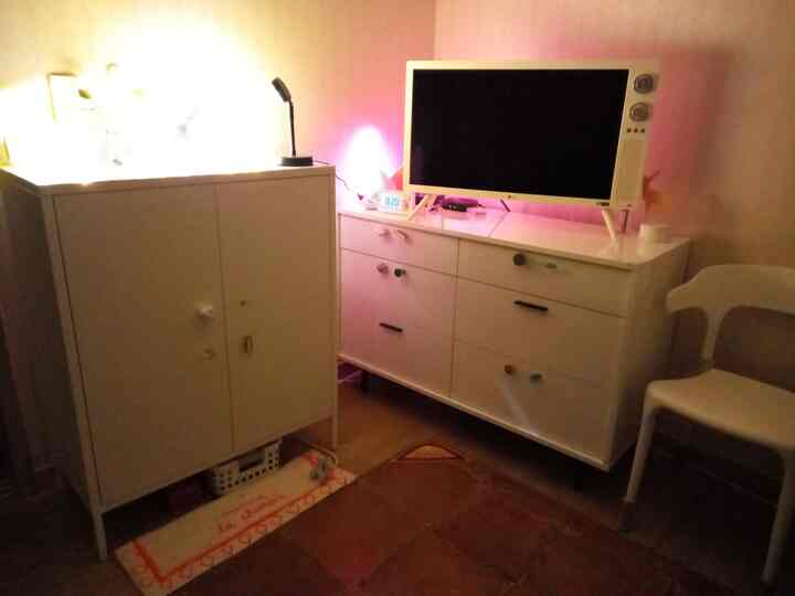 White-toned living room featuring white storage cabinets, retro-style LG TV, and a chair in a cozy setting