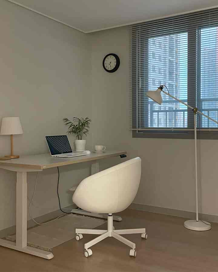Bright white and gray toned study featuring a desk, chair, and floor lamp arranged in a neat home office interior