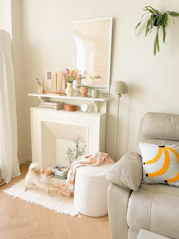 アイボリー色調のリビング、モダンなソファとコンソールテーブル、フロアランプ、ラグ、小さなペット犬がいる落ち着いた雰囲気のインテリア