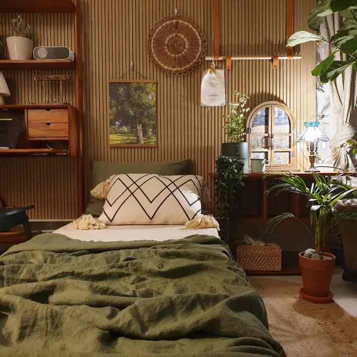 Natural wood tone bedroom featuring a centrally placed bed and desk with abundant plants creating a cozy atmosphere