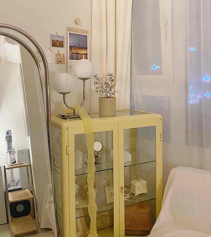 Bright yellow cabinet and white curtains and sofa create a simple and romantic interior space