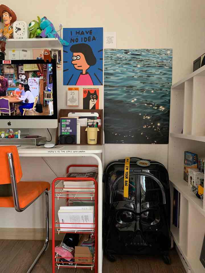 White and black toned study space with an orange chair and black suitcase, creating a modern workspace atmosphere