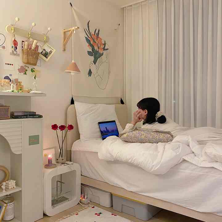 White-toned bedroom featuring a bed with pillows in center, floral wall tapestry, creating a cozy atmosphere