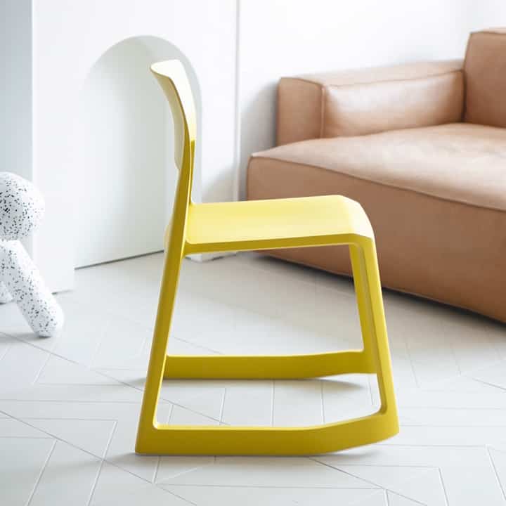 White-toned living room featuring a bright yellow Tip Ton chair and beige leather sofa