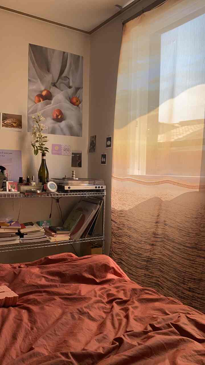 Warm beige bedroom featuring a red duvet cover and a fabric poster depicting an ocean sunset, creating a cozy atmosphere