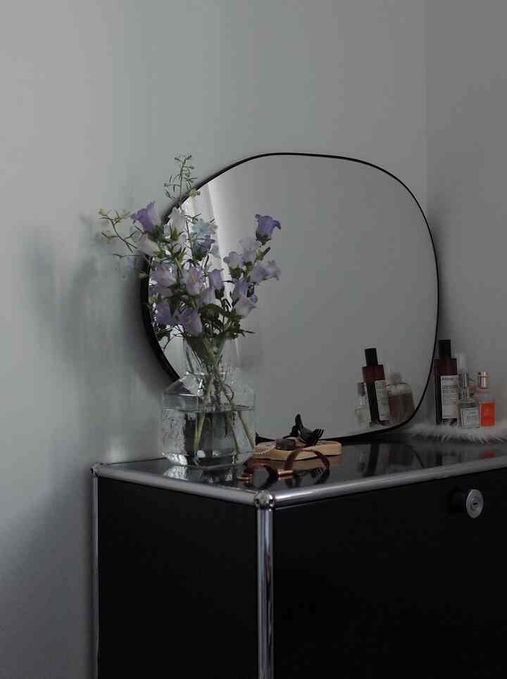 Black USM storage unit topped with a transparent vase holding lavender flowers in a simple, natural interior