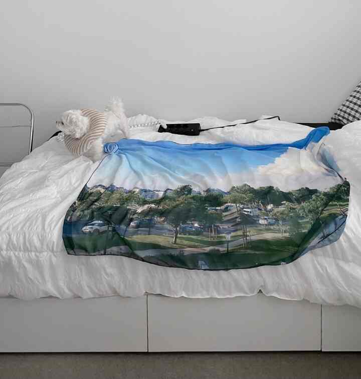 White-toned bedroom featuring a large bed with summer bedding and a small dog for a cozy atmosphere