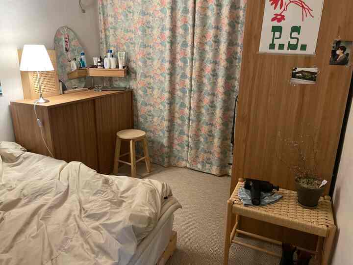 ベージュと木目調の暖かい寝室、ベッドと化粧台、木製のスツールが配置された自然な雰囲気のインテリア