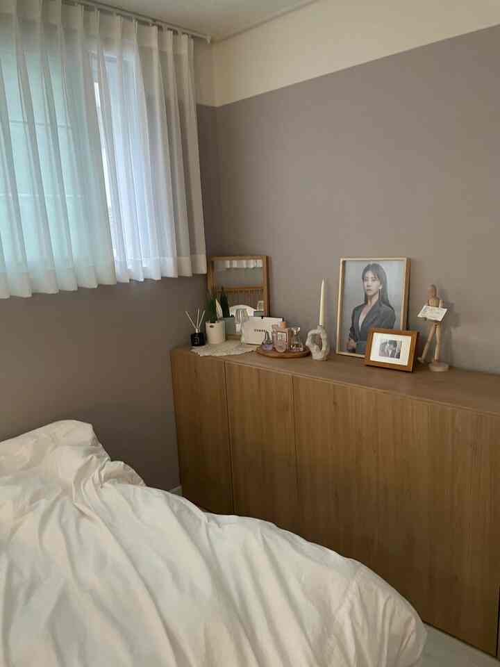 Bedroom with white curtains and natural brown storage cabinet, featuring a clean and hotel-like atmosphere