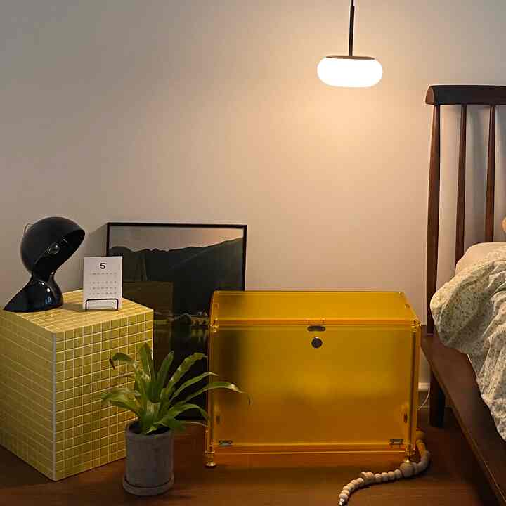 A yellow and brown toned bedroom featuring a yellow transparent storage box, tiled cube, and wooden bed frame creating a cozy space