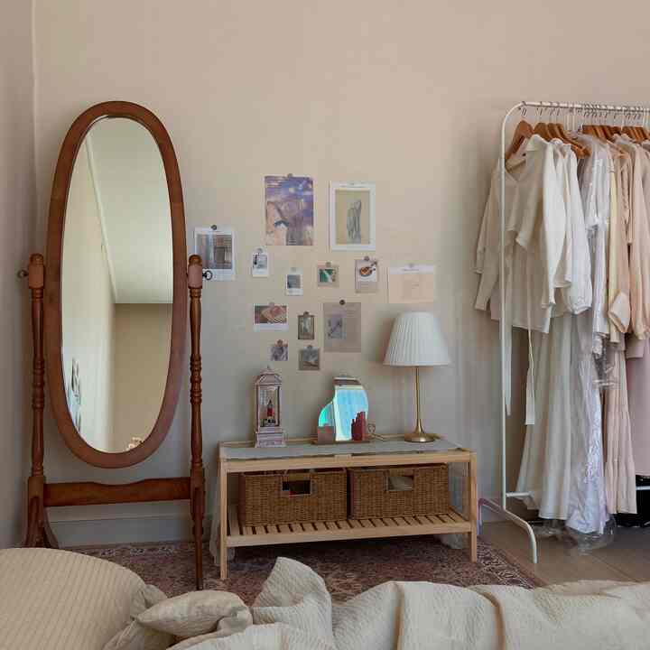 A warm wood-tone walk-in closet featuring a large wooden standing mirror, vanity table, clothing rack and a Persian carpet creating cozy ambiance