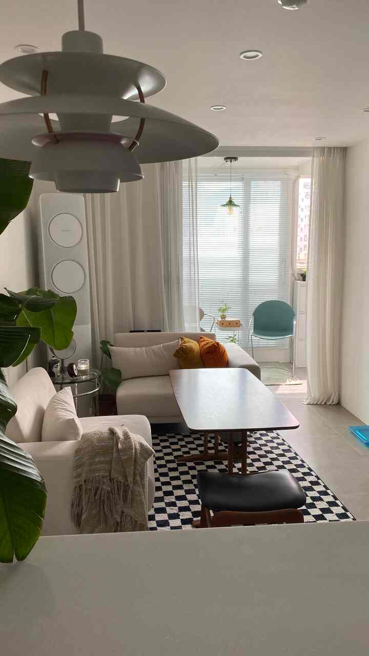 White and brown toned living room featuring two-person sofa, cafe style table and checkered rug with cozy atmosphere