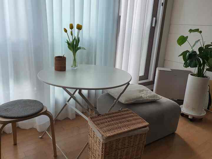 ホワイトとウッドトーンが調和したリビング、丸テーブルとラタンバスケットが配置されたシンプルな空間