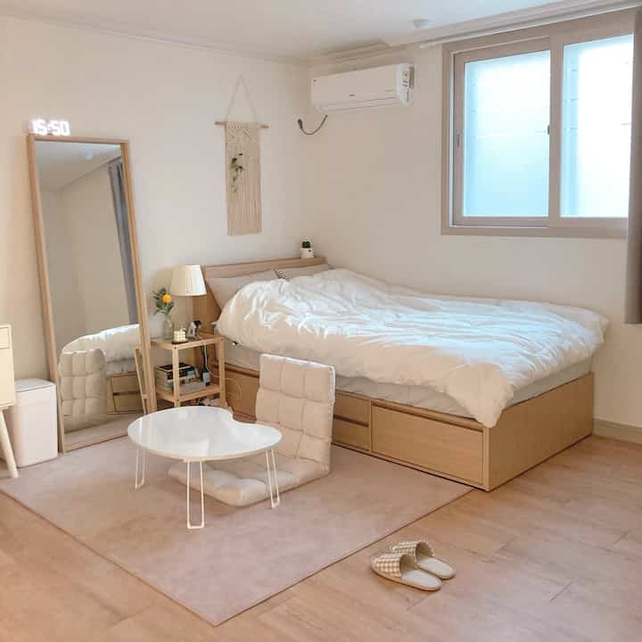 ナチュラルな色調と木目調が調和したワンルーム寝室、木製ベッドと座卓が配置された雰囲気のあるインテリア