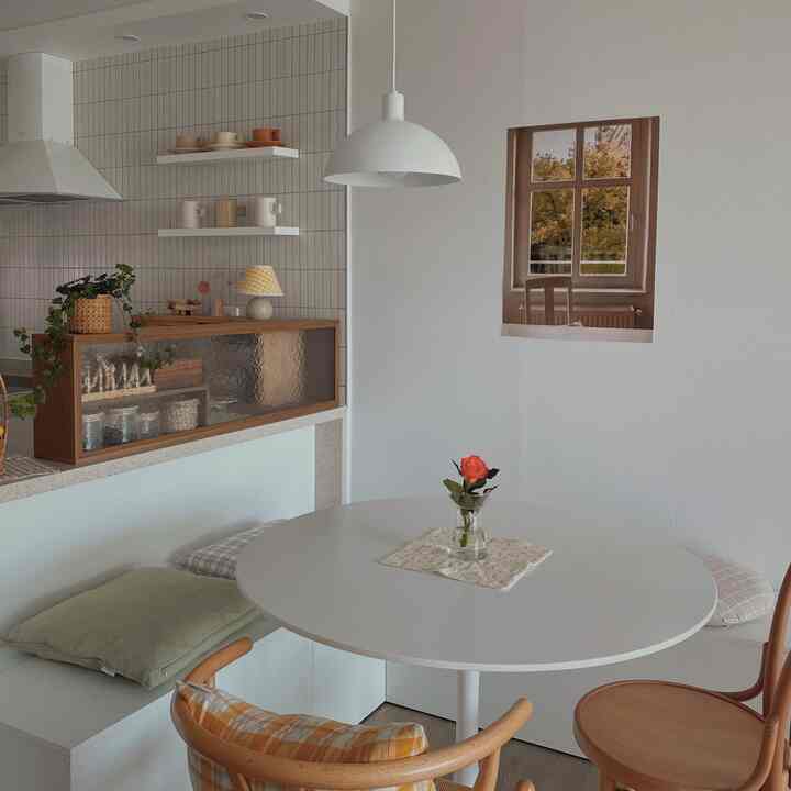 White and natural toned kitchen dining area featuring a round table and bench seating with cozy atmosphere