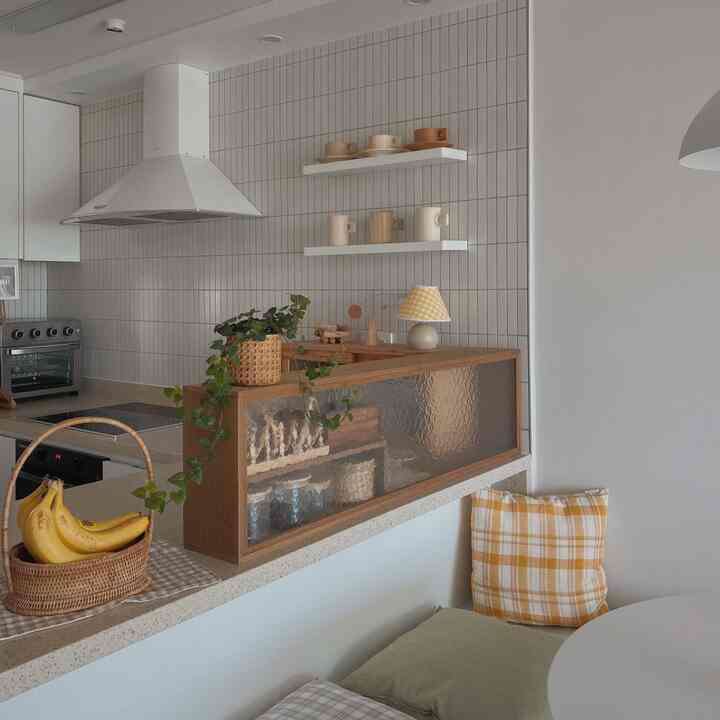 Cafe style kitchen with white walls and wood tones, featuring a bench with checkered cushions and cozy natural decor