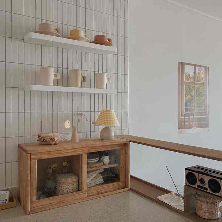 White and wood tone kitchen space featuring floating shelves and a mini cabinet with a clean, cozy atmosphere