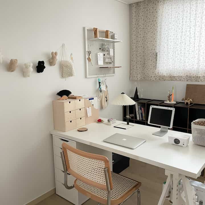 Bright white-toned workspace with wood-tone furniture and bookshelf arranged neatly in a home office