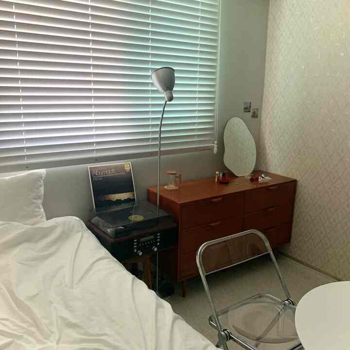 ホワイトと木目調が調和した寝室、すっきりとした家具とブラインドが落ち着いた雰囲気のあるインテリア