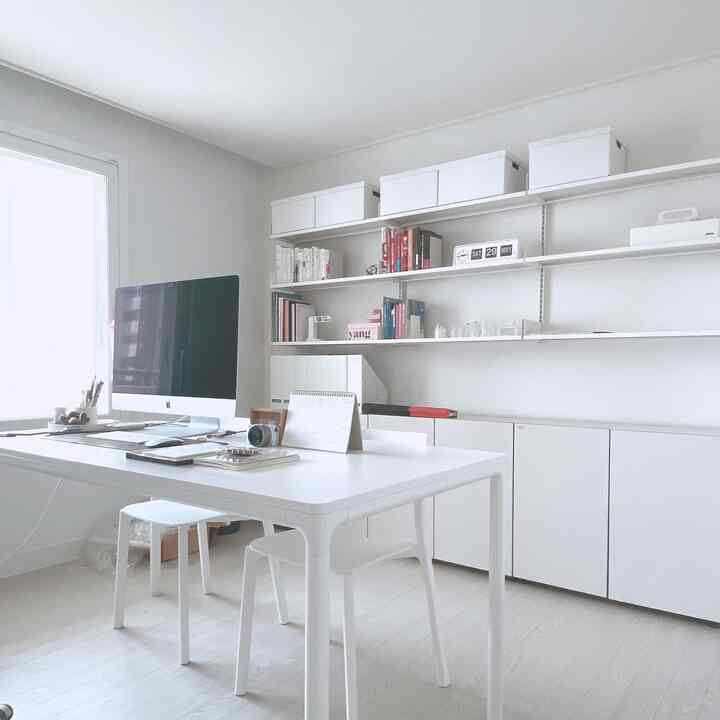 Bright white-toned study featuring a large desk with computer at center and minimal, tidy atmosphere