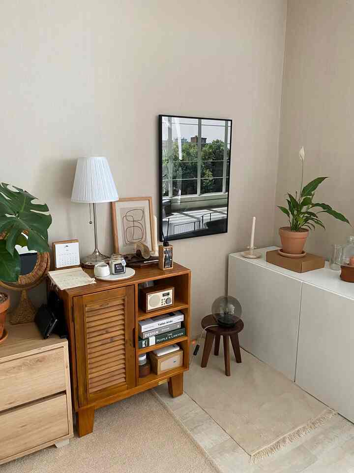 ベージュの壁と木目調の家具、植物、テーブルランプが配置されたナチュラルな雰囲気のリビング