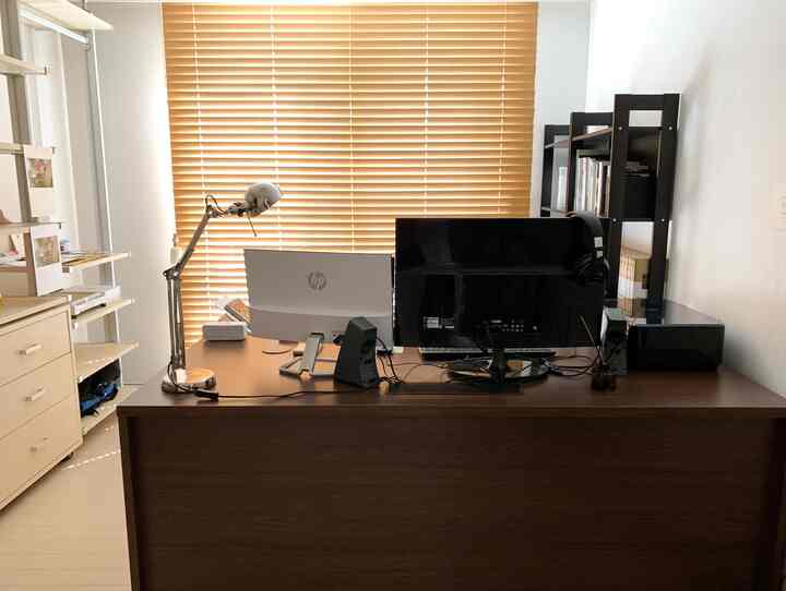 Warm wood-toned study featuring a wooden desk with two monitors arranged simply for work