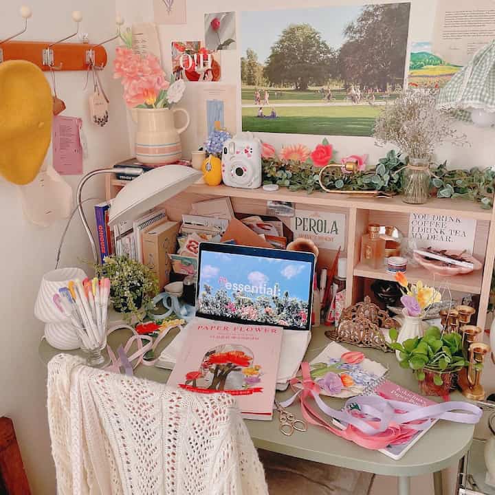 Pastel and green toned home office space featuring a desk with books and paper flowers in a cozy workspace