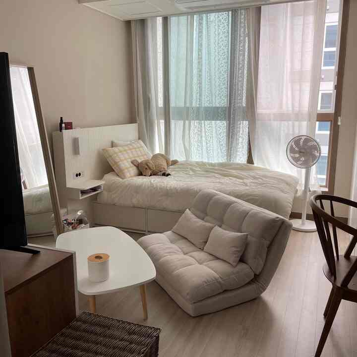 ナチュラルカラーの6坪ワンルーム寝室、ホワイトベッドとベージュのソファベッドが配置された落ち着いた空間