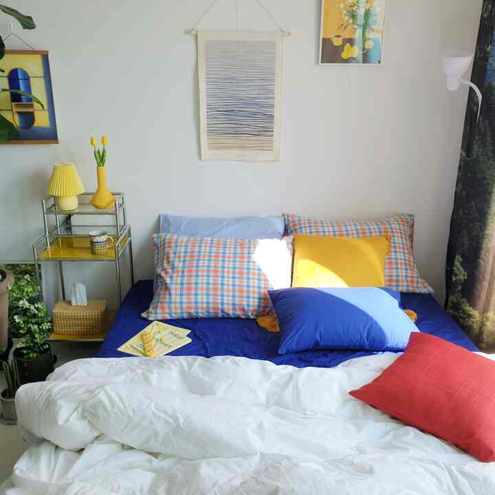 白と青を基調とした6畳の寝室、色とりどりのクッションと枕が置かれた居心地の良い空間