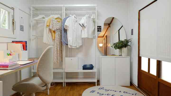 White and wood tone studio apartment walk-in closet with practical storage furniture and desk in a simple space