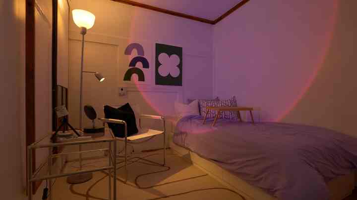 White and purple toned bedroom featuring bed, chair, and floor lamp with cozy ambiance