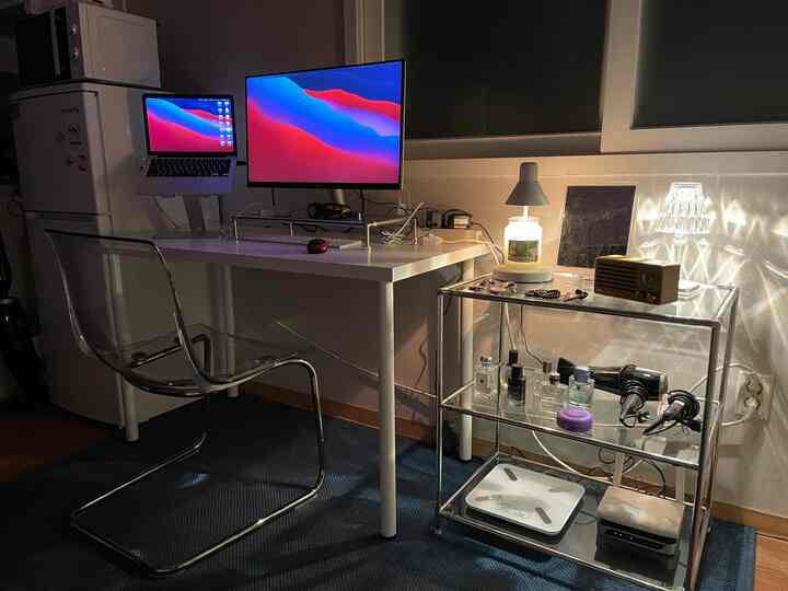 ホワイトとブルーのトーンが特徴的なホームオフィス、透明なアクリル家具とデュアルモニターが配置されたシンプルでモダンなワークスペース