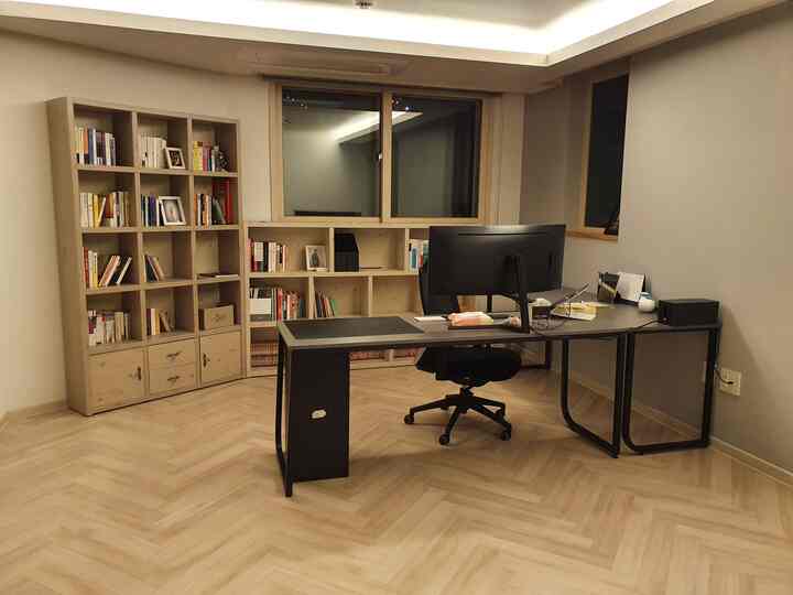 Beige and wood-toned L-shaped study with spacious bookshelves and modern desks arranged in a neat home office space