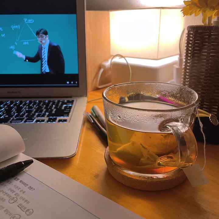 Modern kitchen workspace with warm lighting and transparent teacup on wooden table, creating a cozy study atmosphere