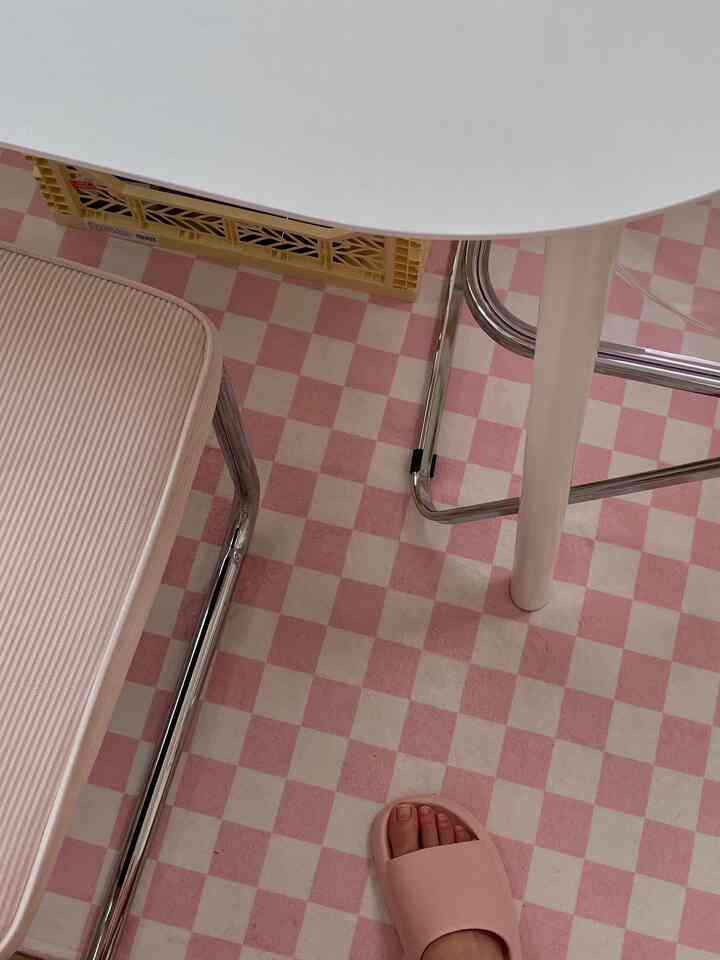 Pink checkered patterned floor with plastic chair in a compact studio apartment styled like a cafe space