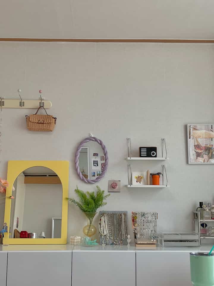 White and natural toned studio apartment featuring yellow-framed mirror and cabinet in a neat photo zone interior