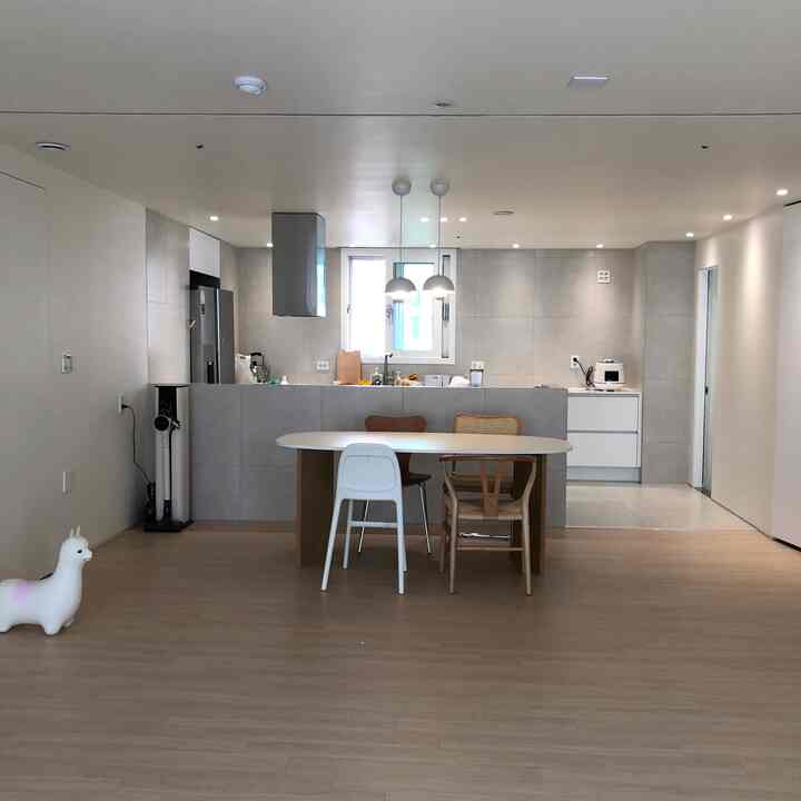 ナチュラルな色調と白い壁が調和したダイニングルームとキッチン、清潔感のある空間に多様な椅子が配置されている