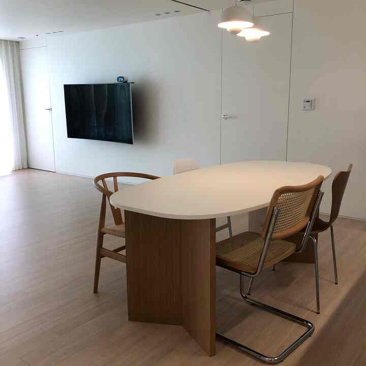 White and wood-toned dining room for four, featuring a central pendant light in a clean and natural setting
