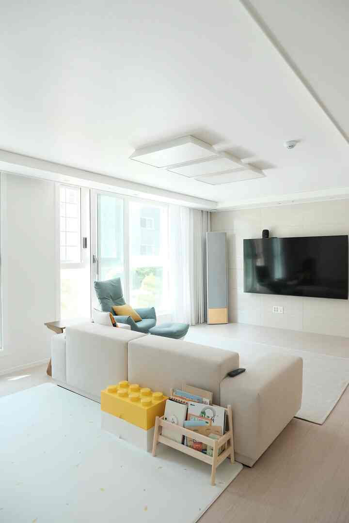 Bright white and beige toned living room featuring a large sofa and children's toy storage creating a cozy family space
