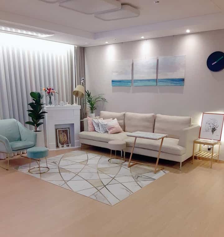 A modern living room in white and natural tones featuring a marble-pattern carpet, a 3.5-seat sofa, and a mint armchair