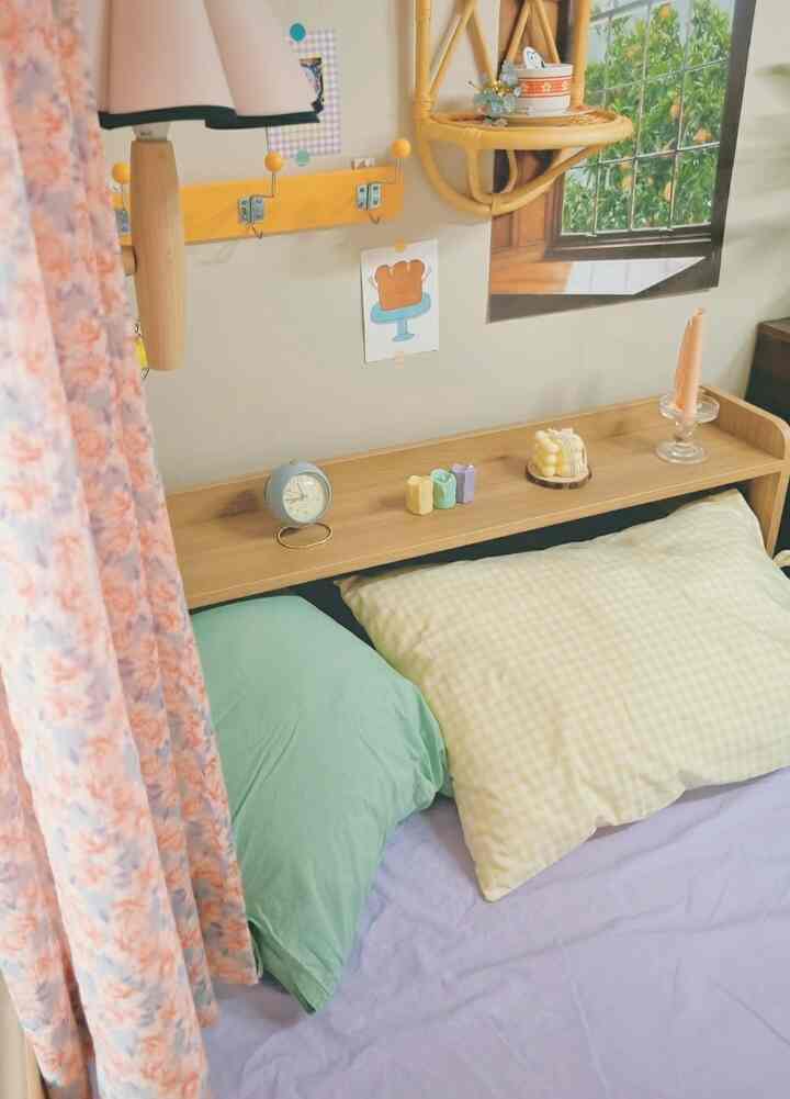 A cozy small bedroom in natural tones and pastel colors featuring a bed with yellow checkered and green pillows, floral curtain on the side